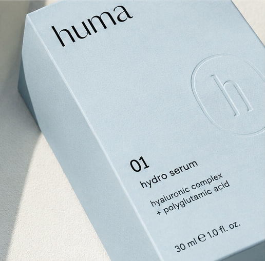 huma 01 hydro serum — astuccio in cartoncino tinto Blue in massa, goffratura a secco del monogramma huma sul fronte, nessun inchiostro. Effetto rilievo visibile solo in luce radente.